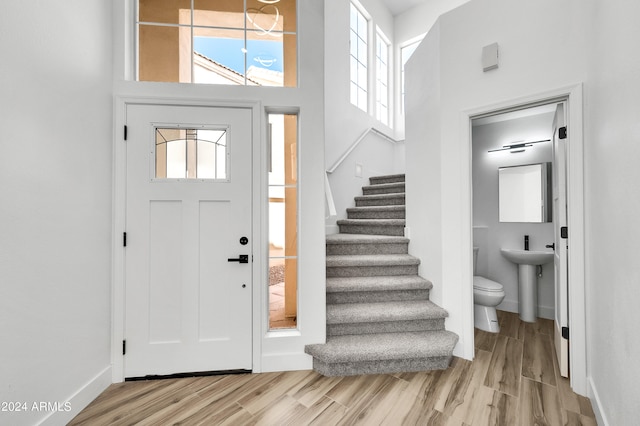 foyer entrance featuring a towering ceiling, light hardwood / wood-style flooring, and sink