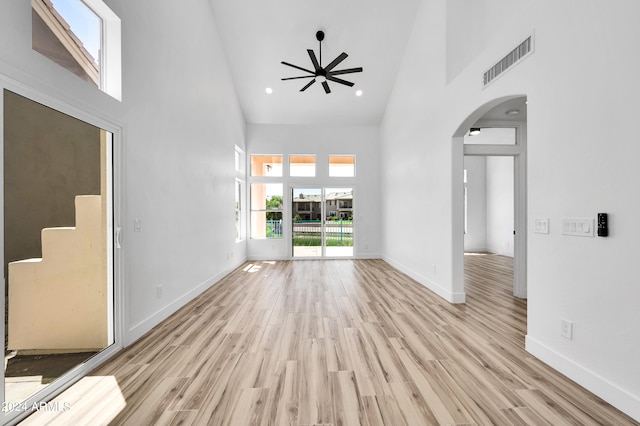 unfurnished living room with light hardwood / wood-style flooring, high vaulted ceiling, and ceiling fan