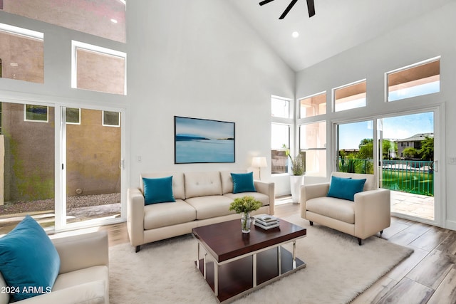 living room featuring ceiling fan, high vaulted ceiling, and light wood-type flooring