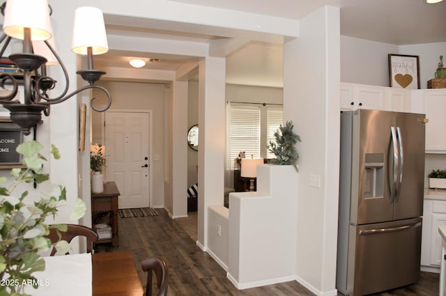 kitchen with dark hardwood / wood-style flooring, stainless steel fridge with ice dispenser, and white cabinets