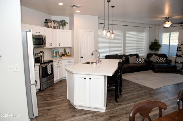 kitchen featuring pendant lighting, white cabinetry, sink, a kitchen island with sink, and stainless steel appliances