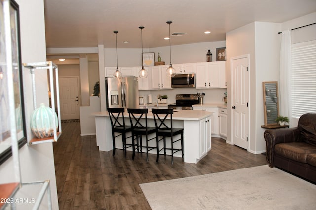 kitchen featuring a breakfast bar area, appliances with stainless steel finishes, hanging light fixtures, white cabinets, and a kitchen island