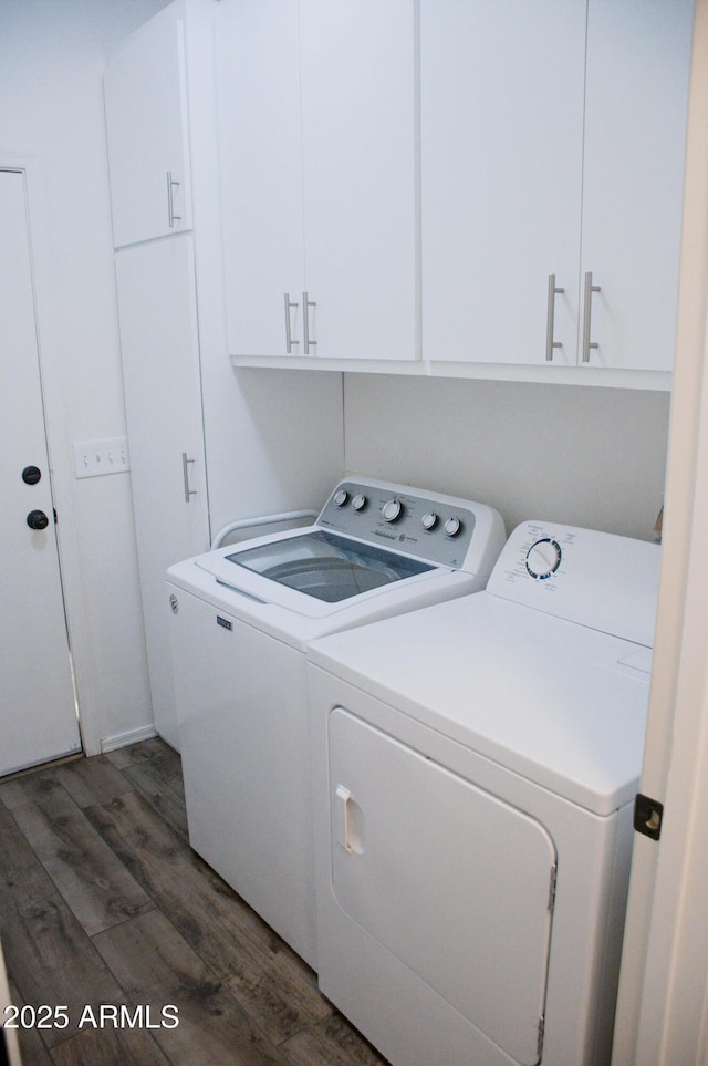 washroom featuring cabinets, washing machine and clothes dryer, and dark wood-type flooring