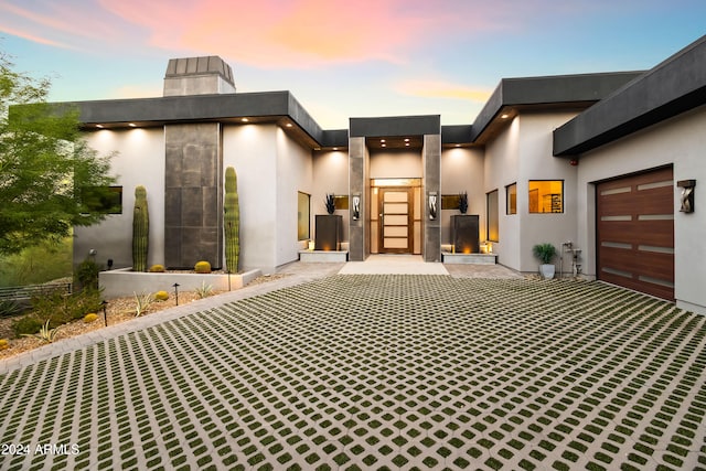 exterior entry at dusk featuring a garage