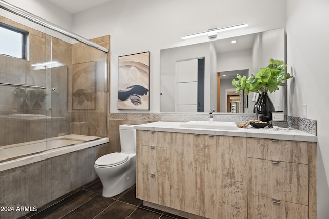 full bathroom featuring vanity, toilet, tile patterned floors, and combined bath / shower with glass door