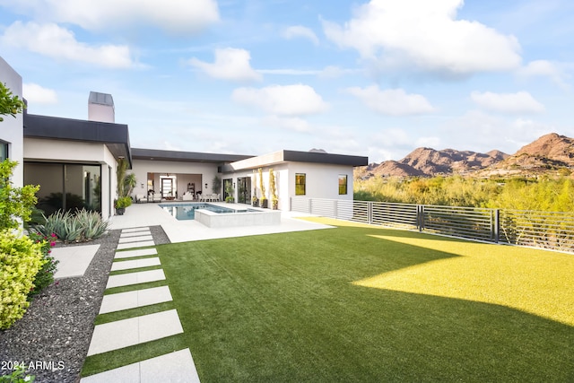 view of yard featuring an in ground hot tub, a mountain view, and a patio