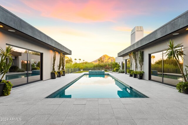 pool at dusk with a patio and a mountain view