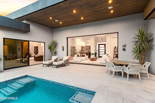 back house at dusk with a patio and outdoor lounge area