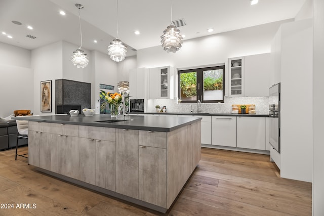 kitchen with a large island, light hardwood / wood-style flooring, white cabinetry, and hanging light fixtures