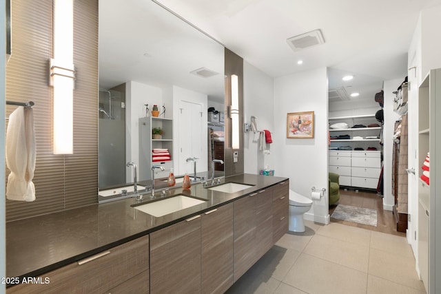full bathroom featuring a walk in closet, tile patterned floors, and a sink