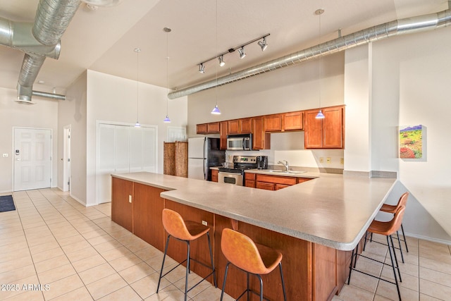 424 S 2nd St Unit 203, Phoenix, AZ 85004 - kitchen featuring a towering ceiling, appliances with stainless steel finishes, light tile patterned floors, brown cabinets, and a breakfast bar