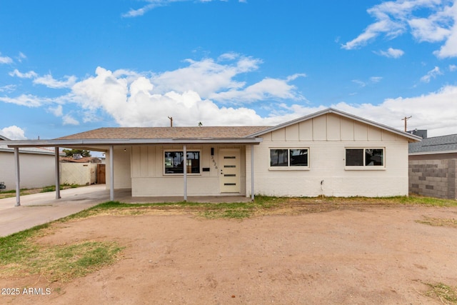 ranch-style house featuring a carport, board and batten siding, brick siding, and fence