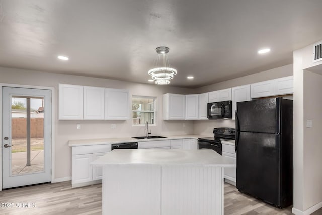 kitchen with a sink, black appliances, light countertops, and white cabinetry