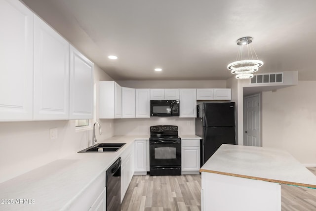 kitchen featuring white cabinetry, black appliances, visible vents, and a sink