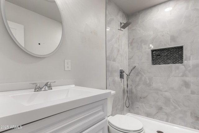 bathroom featuring vanity, toilet, and a tile shower