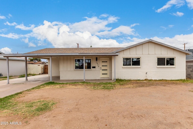 ranch-style home with fence, driveway, brick siding, a carport, and board and batten siding