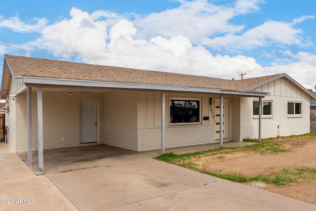 ranch-style house featuring brick siding, an attached carport, a porch, roof with shingles, and driveway