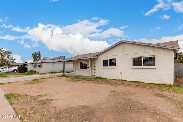 ranch-style home featuring board and batten siding, a carport, brick siding, and driveway