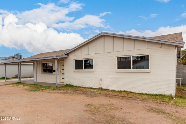 view of front of house featuring brick siding, a patio, a carport, and board and batten siding