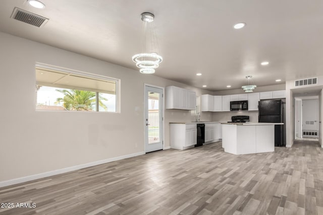 kitchen featuring visible vents, white cabinets, black appliances, and a sink