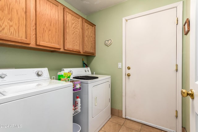 clothes washing area featuring cabinets, light tile patterned floors, and separate washer and dryer