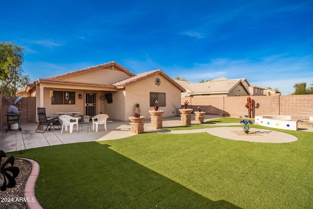 rear view of property with exterior kitchen, a patio area, and a lawn