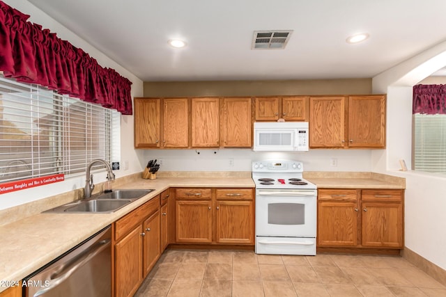 kitchen featuring sink, light tile patterned floors, and white appliances