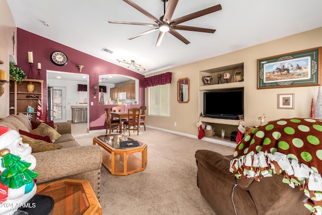 carpeted living room with ceiling fan, built in features, and vaulted ceiling