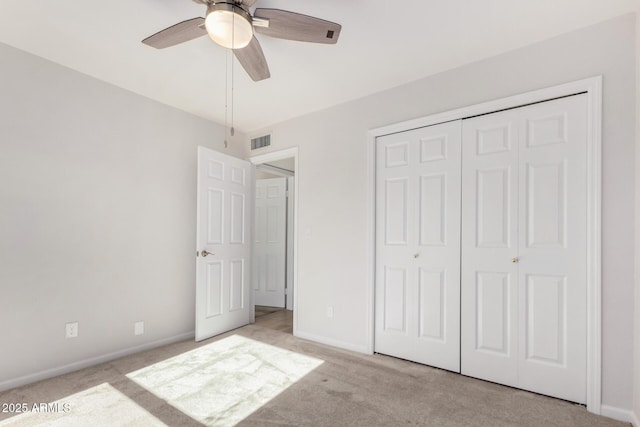 unfurnished bedroom featuring ceiling fan, a closet, and light carpet