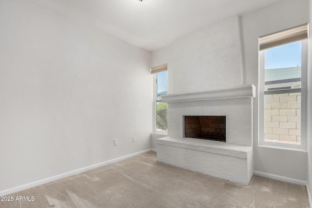 unfurnished living room with a fireplace, light carpet, and a water view