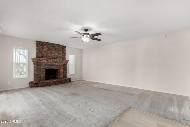 unfurnished living room with a brick fireplace, ceiling fan, and light colored carpet