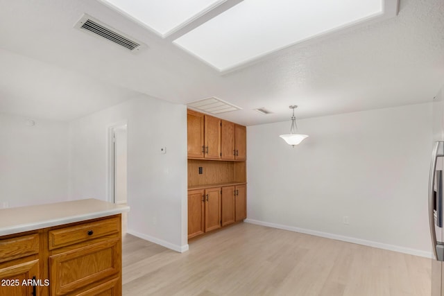 kitchen featuring light hardwood / wood-style floors, stainless steel fridge, and hanging light fixtures