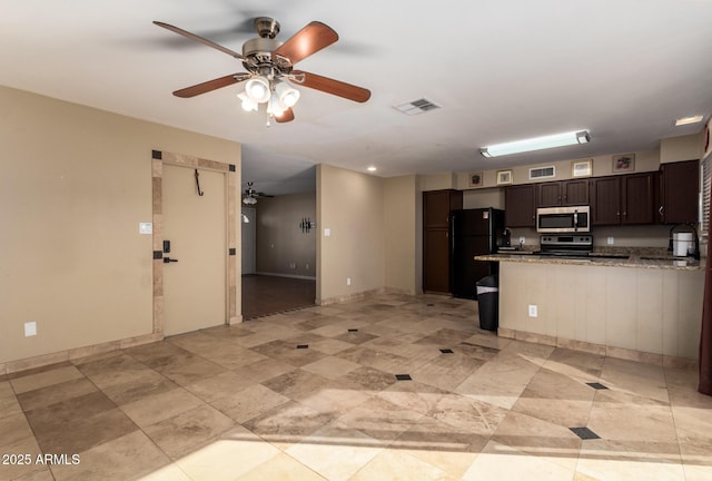 kitchen with appliances with stainless steel finishes, dark brown cabinets, a kitchen bar, and ceiling fan