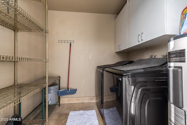 laundry area featuring cabinets, electric water heater, light tile patterned floors, and washing machine and clothes dryer