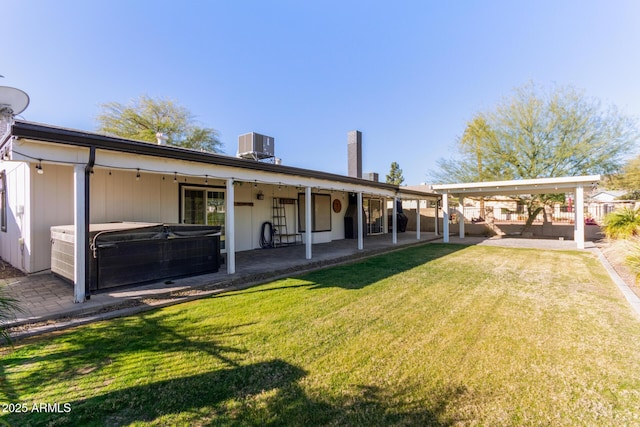 rear view of property with a lawn, central AC, a hot tub, and a patio