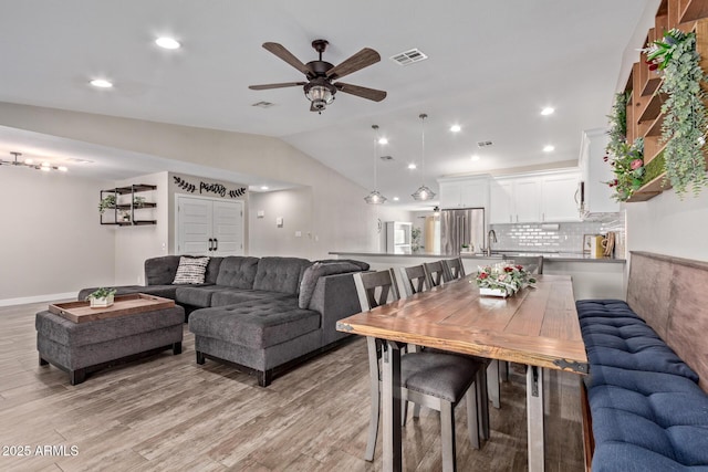 dining area featuring light hardwood / wood-style floors, ceiling fan, vaulted ceiling, and sink