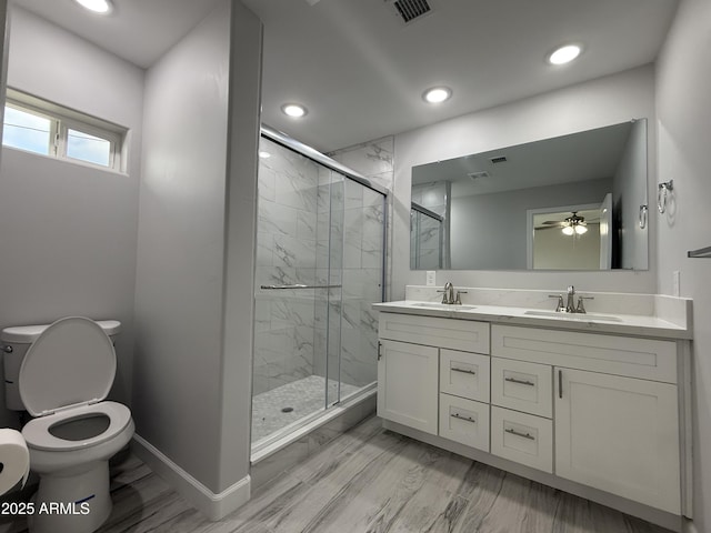 bathroom featuring toilet, vanity, a shower with door, ceiling fan, and hardwood / wood-style floors