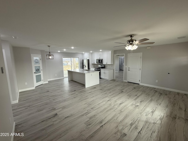 kitchen with white cabinetry, a center island, light hardwood / wood-style flooring, appliances with stainless steel finishes, and pendant lighting