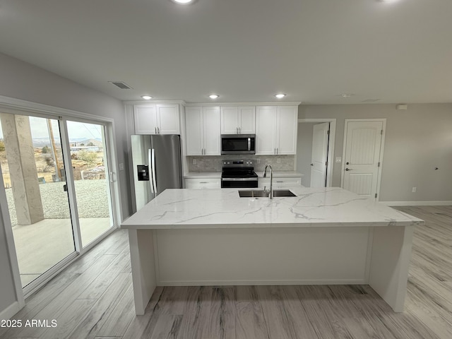 kitchen with sink, stainless steel appliances, white cabinets, and light stone countertops