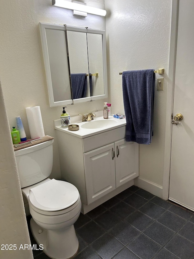 bathroom featuring tile patterned floors, baseboards, toilet, and vanity