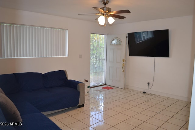 living area featuring light tile patterned flooring, ceiling fan, and baseboards