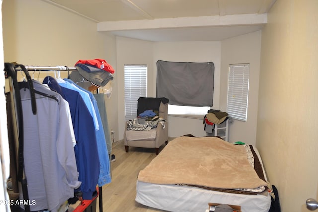 bedroom featuring beamed ceiling and wood finished floors