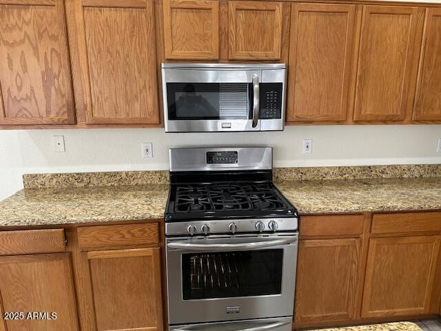 21192 N 80th Ln, Peoria, AZ 85382 - kitchen featuring stainless steel appliances, light stone counters, and brown cabinetry