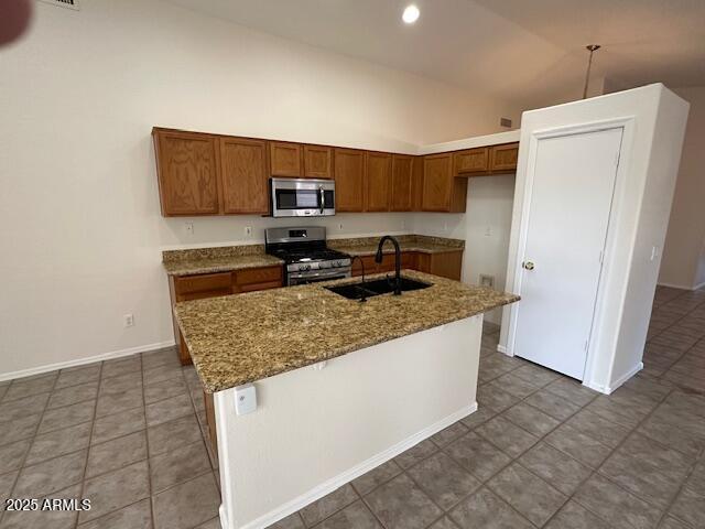 21192 N 80th Ln, Peoria, AZ 85382 - kitchen with stainless steel appliances, a sink, brown cabinetry, stone counters, and high vaulted ceiling