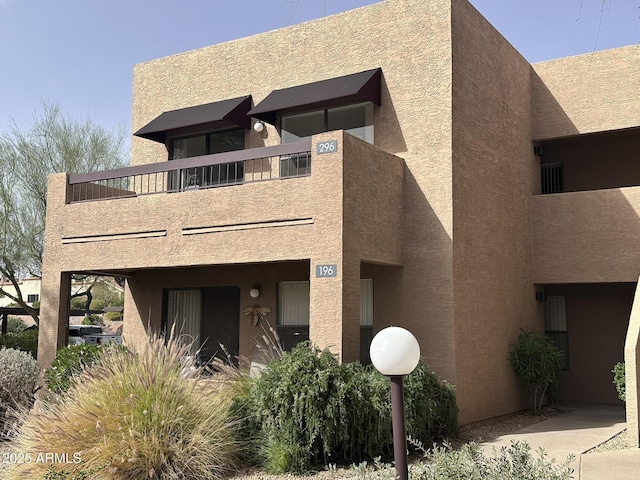 view of front facade with a balcony and stucco siding