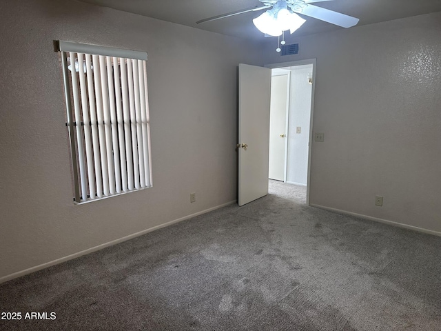 spare room with ceiling fan, carpet floors, visible vents, and baseboards