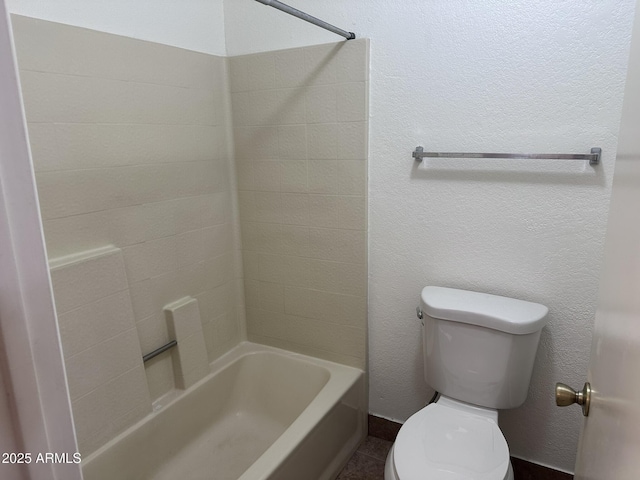 bathroom with a textured wall, shower / tub combination, and toilet