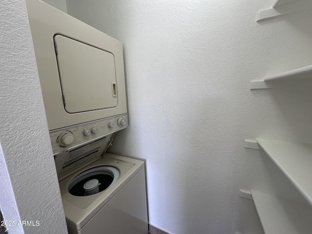 laundry area with laundry area, a textured wall, and stacked washer and clothes dryer