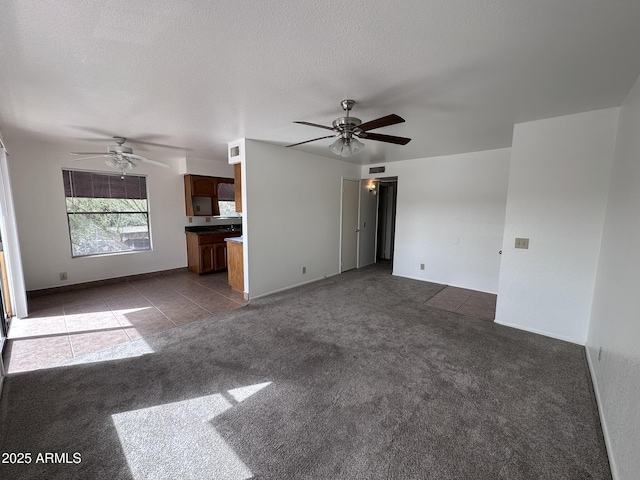 unfurnished living room featuring visible vents, dark carpet, a textured ceiling, and ceiling fan