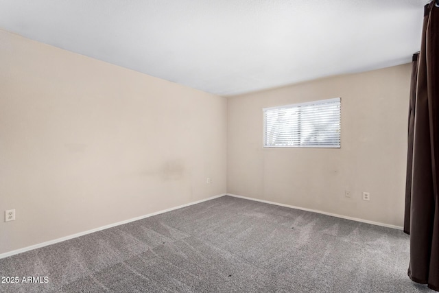 carpeted spare room featuring baseboards